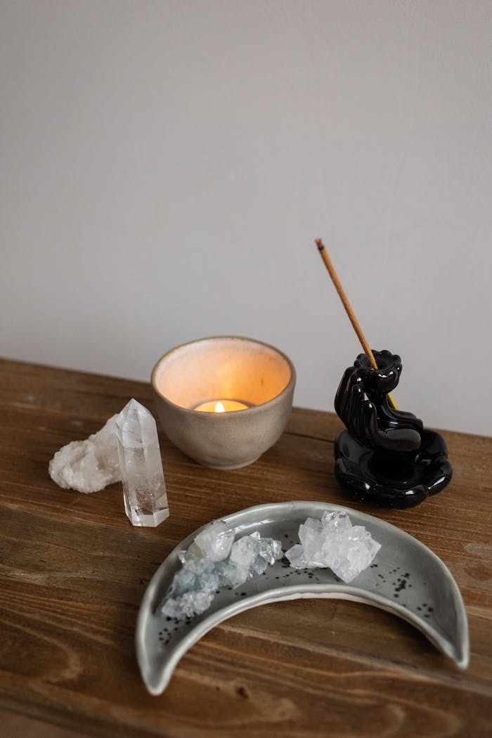 Serene arrangement of a candle, crystals, and incense for a tranquil atmosphere.